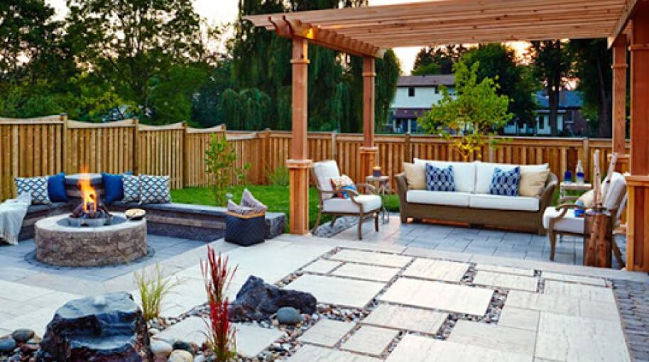 Backyard patio decorated with a fire pit, chairs, couches, and cushions.