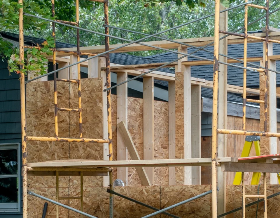 House extension framing in progress with timber wall studs and roof trusses adding living space.