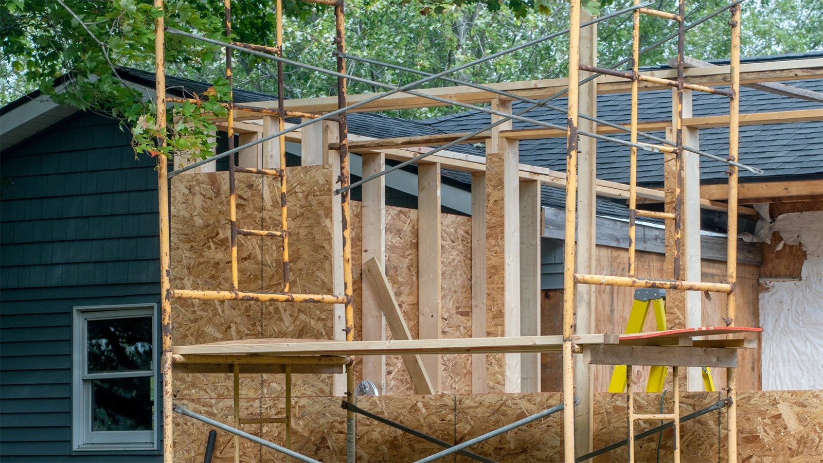 House extension framing in progress with timber wall studs and roof trusses adding living space.