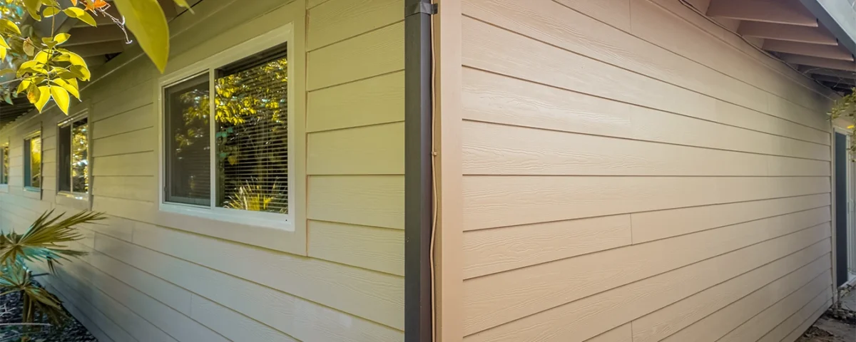 House exterior showing old yellow siding on one side and new tan siding on the other