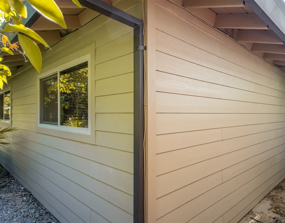 House exterior showing old yellow siding on one side and new tan siding on the other