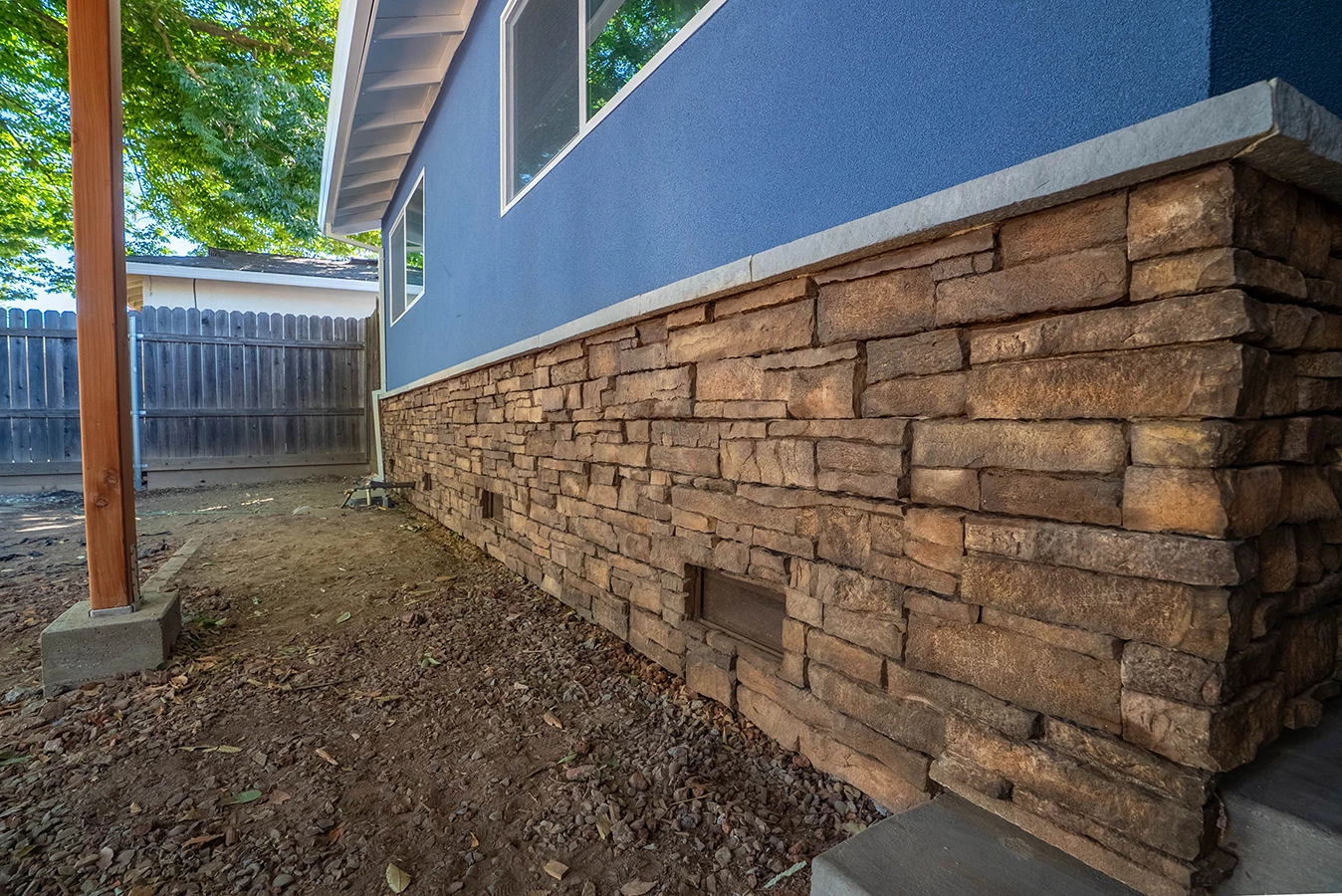 House exterior with blue stucco upper wall and stacked stone veneer along the lower foundation