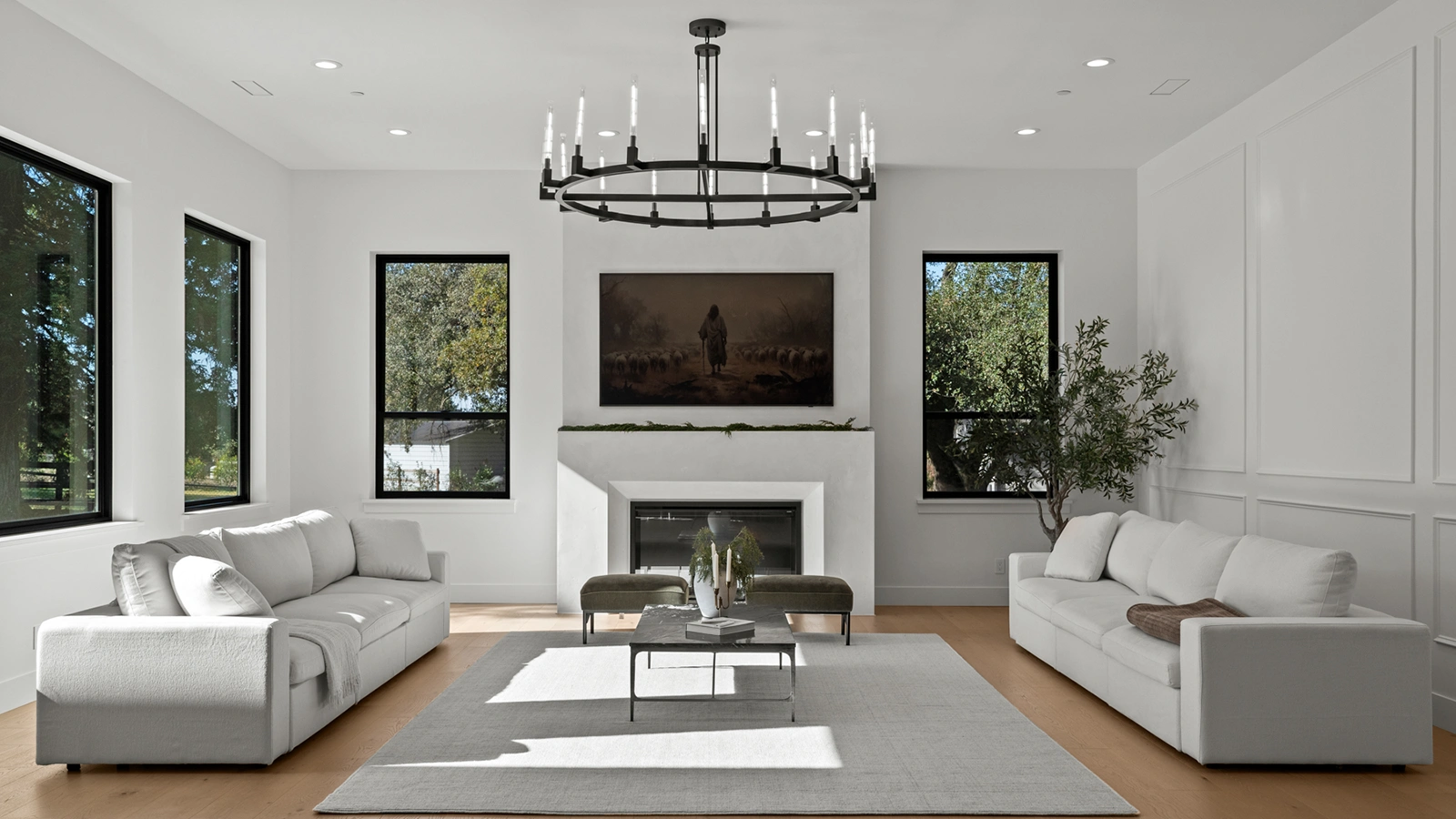 Bright whole home remodel featuring a modern living room with white sofas, fireplace, wood floors, and large windows.